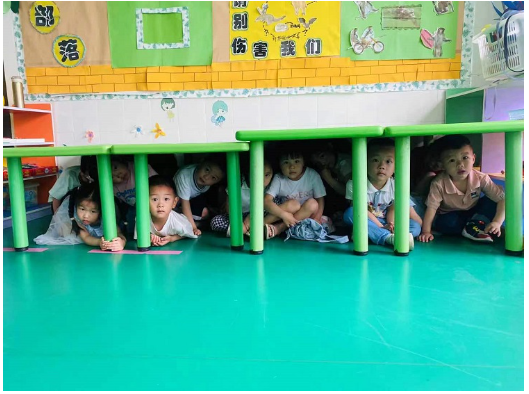 鲤鱼江幼儿园的孩子们躲在课桌下面，在干什么呢？
